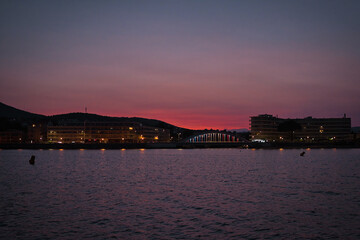 Obraz premium Vivid pink and red sunset over St. Maxime and the sea, view from ferry between St. Tropez and St. Maxime