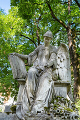 sehr großer Engel sitzt auf einem Grabstein wie auf einem Stuhl Alter Südfriedhof München