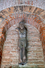 sehr alte Jesusfigur ohne Arme an einer Ziegelwand Alter Südfriedhof München