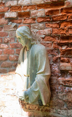 eine halbe Jesusfigur vor einer Ziegelmauer Alter Südfriedhof München