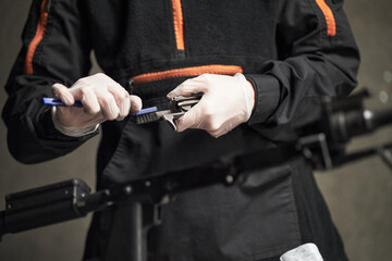 Caucasian young adult man wearing protective gloves cleaning firearm with brush in forensic laboratory, focusing on evidence processing and crime scene investigation procedures