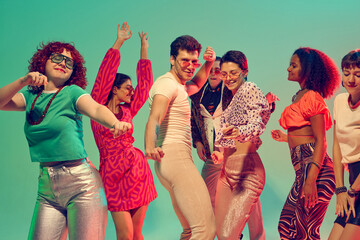 Diverse group of friends dancing joyfully under neon lights. Concept of party culture, celebration, youth lifestyle, music expression and collective happiness.