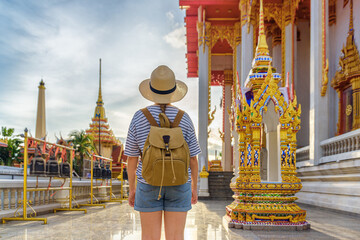 Female tourist in hat with backpack at a Buddhist temple