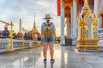Female tourist in hat with backpack at a Buddhist temple