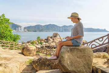 Woman is working on a laptop at a scenic location
