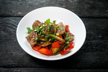 meat with paprika and asparagus in a white plate on a dark background