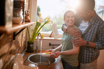 Multiethnic couple washing dishes in the kitchen.