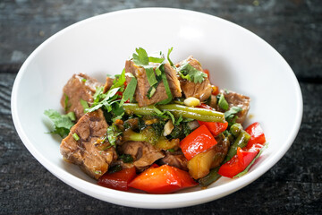 meat with paprika and asparagus in a white plate on a dark wooden background macro photo