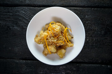 sauteed cauliflower with orange zest in a white plate on a dark background