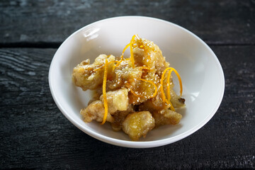 sauteed cauliflower with orange zest in a white plate on a dark background