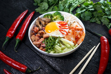bibimbap with sprouts and egg in a white plate on a dark charcoal background