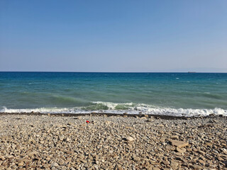 scenic view of the sea shore with pebbles on a clear day