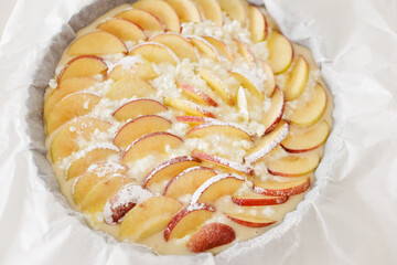 Delicious apple pie baking in round baking pan with parchment paper