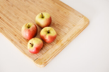 Fresh red apples resting on wooden cutting board