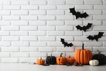 Halloween pumpkins and decorative bats against a white brick wall background.