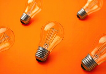 Multiple incandescent light bulbs arranged in a pattern on a vibrant orange background symbolizing ideas and creativity.