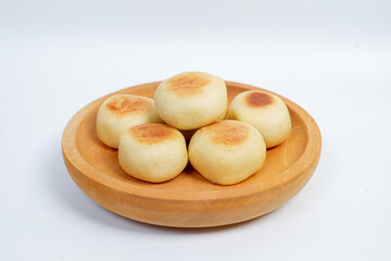 Close up view of delicious Bakpia, round pastry filled with sweet green bean paste, a specialty traditional snack from Yogyakarta, Indonesia. Bakpia on a wooden plate Isolated on white background.