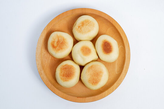 Top view of delicious Bakpia, round pastry filled with sweet green bean paste, a specialty traditional snack from Yogyakarta, Indonesia. Bakpia on a wooden plate Isolated on white background.