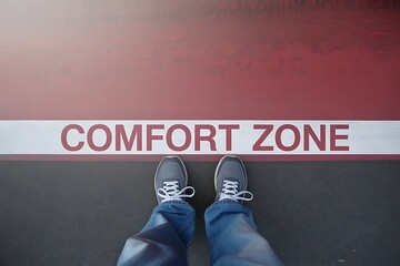 Standing at the edge of the comfort zone a person s feet are positioned to decide whether to step into the unknown or remain in the familiar
