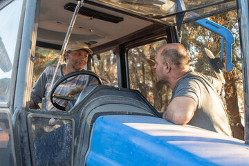 Trabajadores en maquinaria agrícola trabajando y conversando, primer plano