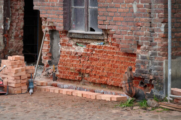 Two workers in construction gear inspecting the red brick facade of a historical building under renovation in Księży Młyn, Łódź © sebastiangora