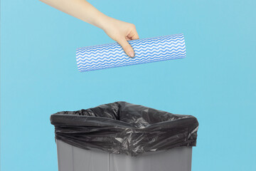 throwing a roll of disposable kitchen towels into the trash, outstretched hand with a roll of...