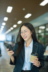 Businesswoman standing typing on mobile phone in modern building