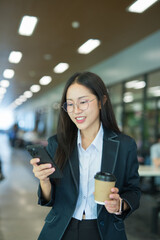 Businesswoman standing typing on mobile phone in modern building