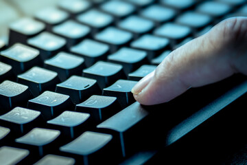 Close-up of a finger pressing the Spacebar key on a black computer keyboard, symbolizing technology, communication, and digital interaction