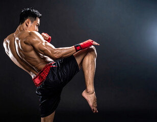 Muay thai fighter kicking with knee on black background