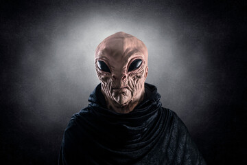 Mysterious humanoid alien at night over dark misty background
