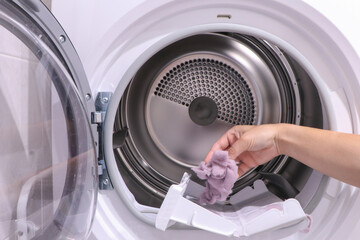 close up female hand taking lint out from dirty air filter of dryer machine after drying. cleaning...
