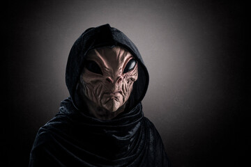 Mysterious humanoid alien at night over dark misty background
