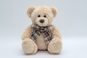 Obraz premium Cute Beige Teddy Bear with Plaid Bow and Big Head on White Background