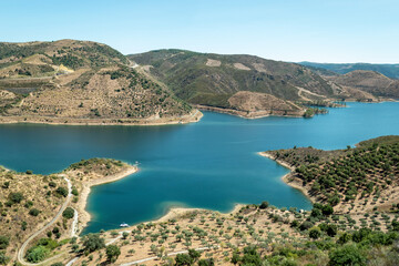 Fototapeta premium O rio Sabor e a beleza natural da paisagem em meio às montanhas cobertas por vegetação e um céu azul em Portugal