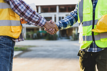 Construction workers shaking hands at construction site, agreement and partnership in a project.