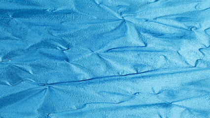 Blue foil texture with shiny metallic surface and wrinkled pattern, abstract luxury background for design and decoration.