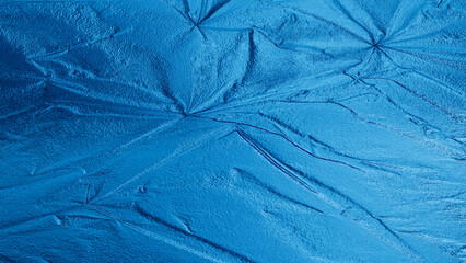 Blue foil texture with shiny metallic surface and wrinkled pattern, abstract luxury background for design and decoration.