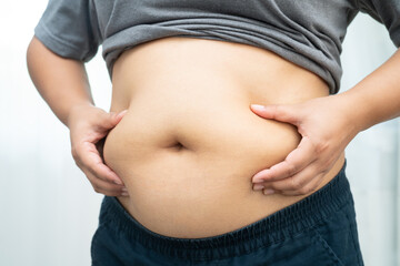 Asian woman use hand to squeeze fat belly big size overweight and obesity.
