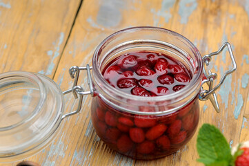 Dogwood berry jam in a small jar on a wooden background