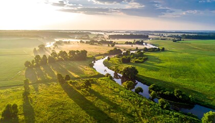 Aerial view of a meandering river through a lush green landscape at sunrise