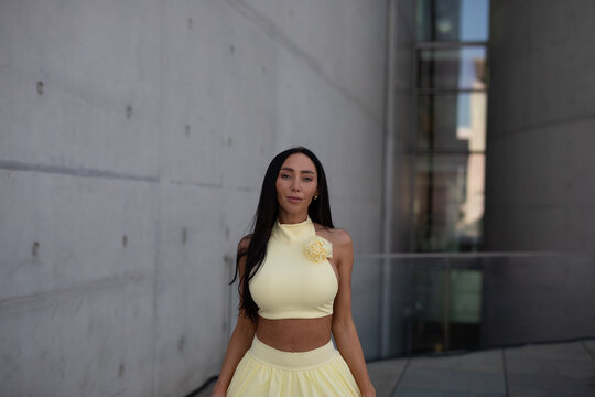 young woman in yello short dress walking on the street in the evening