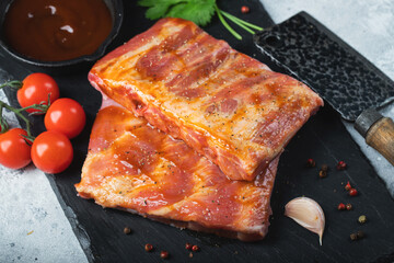 Ready for BBQ raw pork spare ribs with barbecue sauce. Black background. Top view