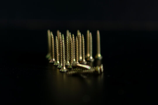 A bunch of screws are on a black background