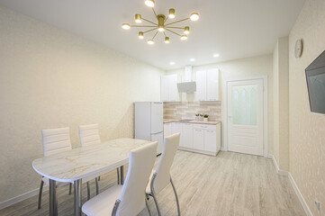 Bright kitchen and dining area with white cabinets, marble table, and modern lighting