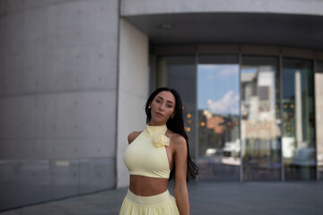 young woman in yello short dress walking on the street in the evening