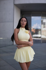 young woman in yello short dress walking on the street in the evening