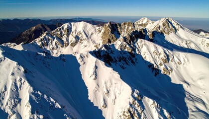 Aerial View of Snowy Mountain Ridges with Blue Shadows