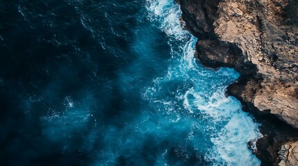 Fototapeta premium Dramatic aerial view of ocean waves crashing against rocky cliffs, creating a mesmerizing display of power and beauty from above