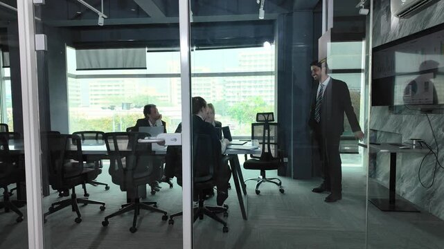 Corporate Meeting in Progress: A group of business professionals engage in a discussion around a conference table in a modern meeting room.